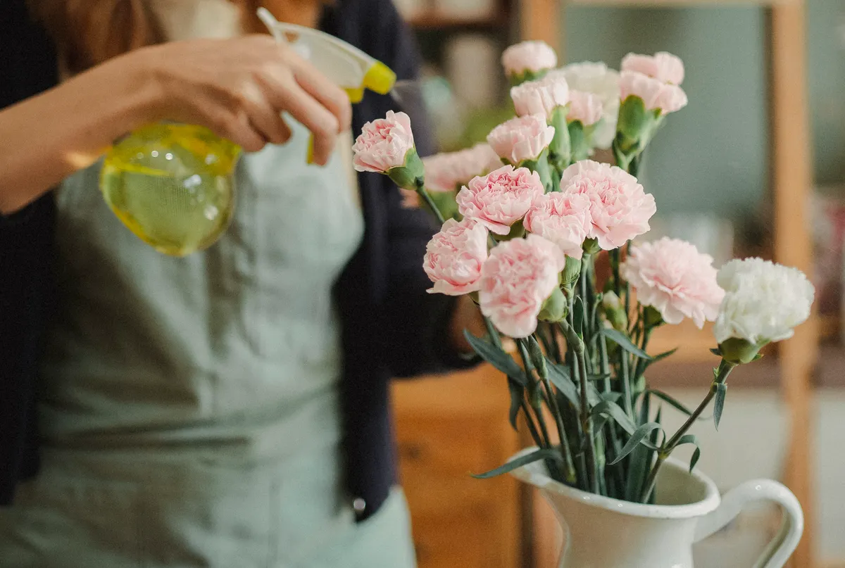 Fleuriste vaporisant de l'eau sur un bouquet fraîchement composé — Jardin Secret d'Alésia